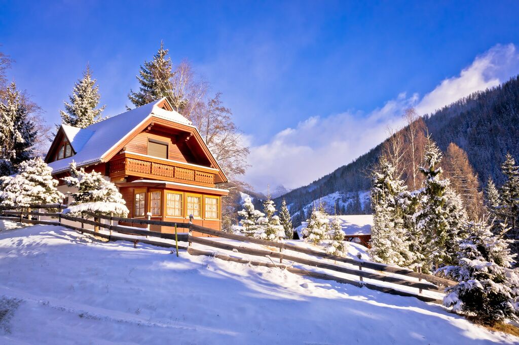 Ferienhaus in Holzbauweise in den österreichischen Alpen im Winter bei schönem Wetter.